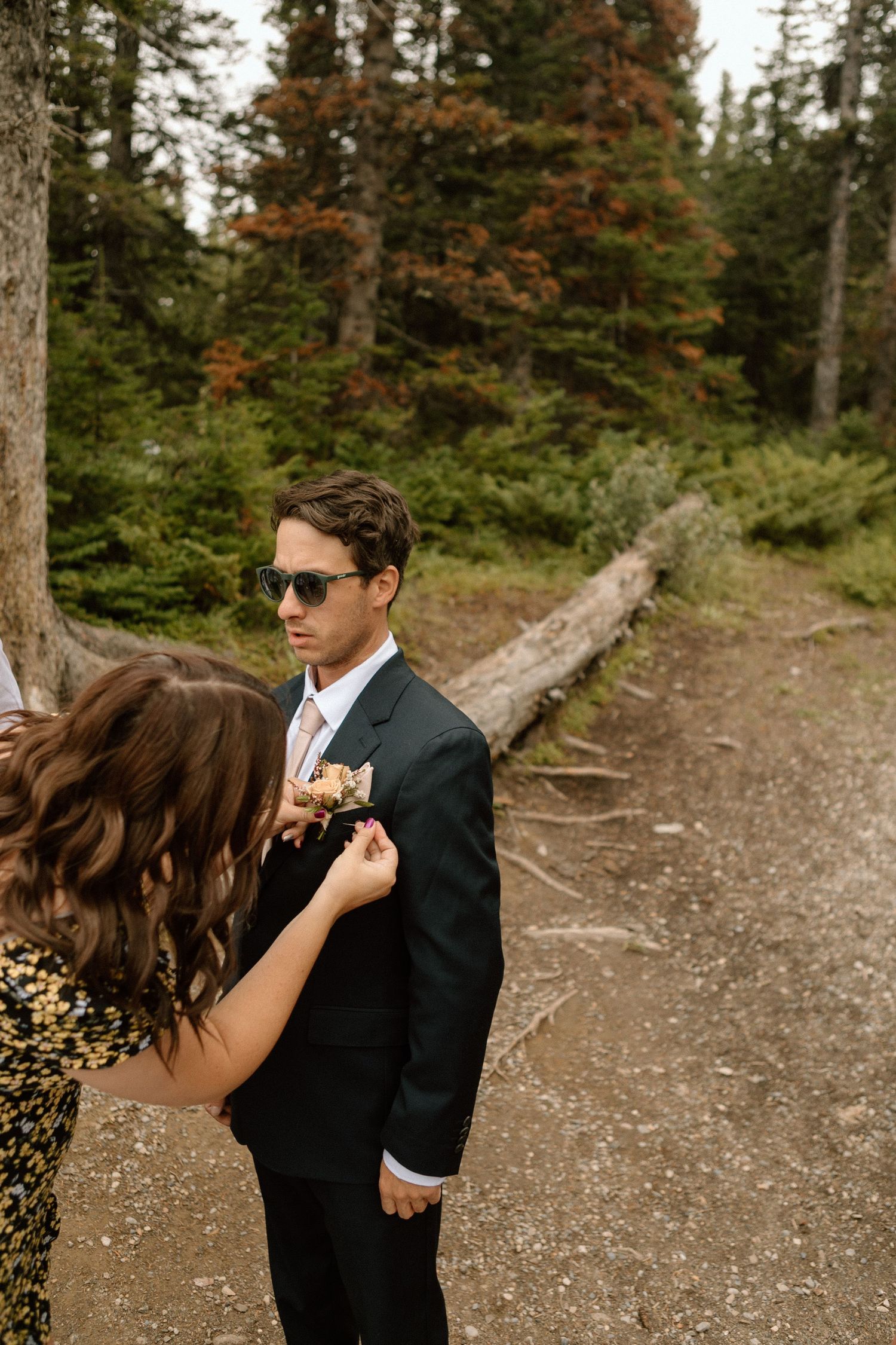 Wedding photo taken on forest trail with evergreen trees in background.