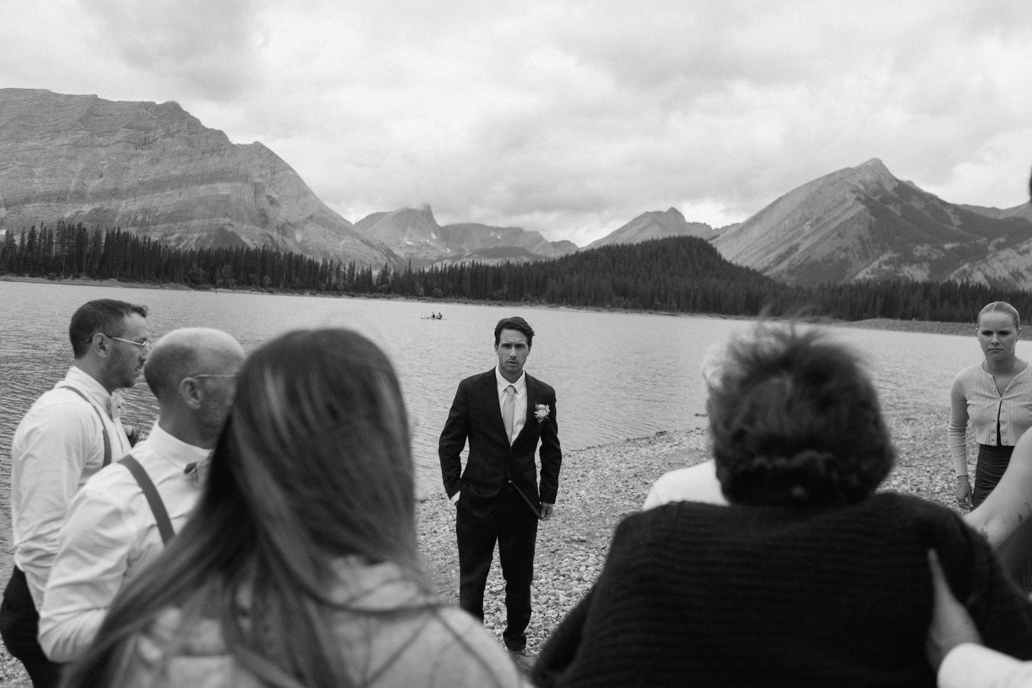 Wedding ceremony with mountain lake backdrop and dramatic cloudy sky.