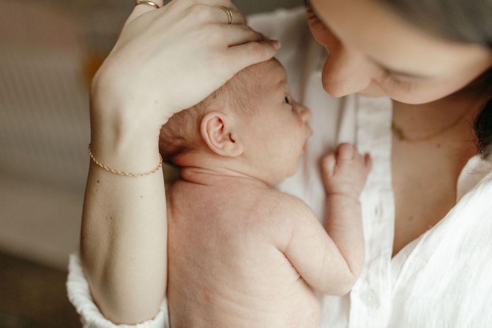 Intimate moment of baby being held and cared for against white background. Virginia/ North Carolina Newborn In-Home Session