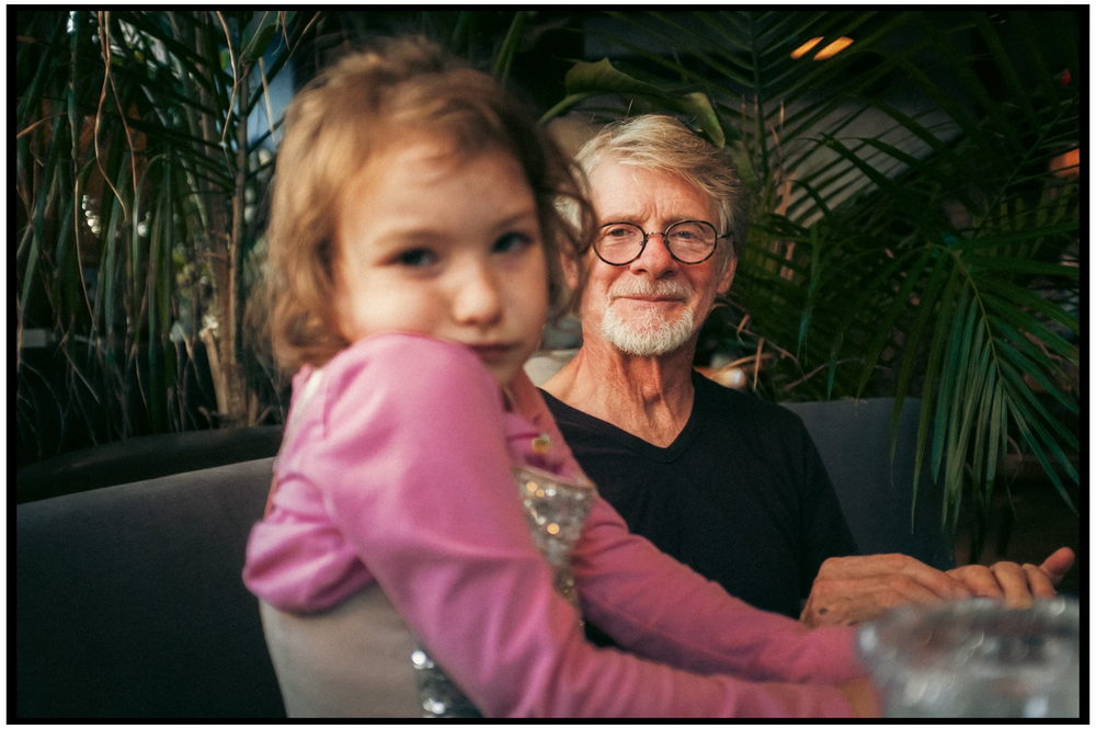 A candid moment captured in a restaurant with lush green plants in the background.