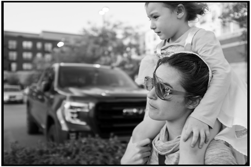 Black and white photo of people enjoying a quiet moment outdoors with a parked pickup truck visible in the background.