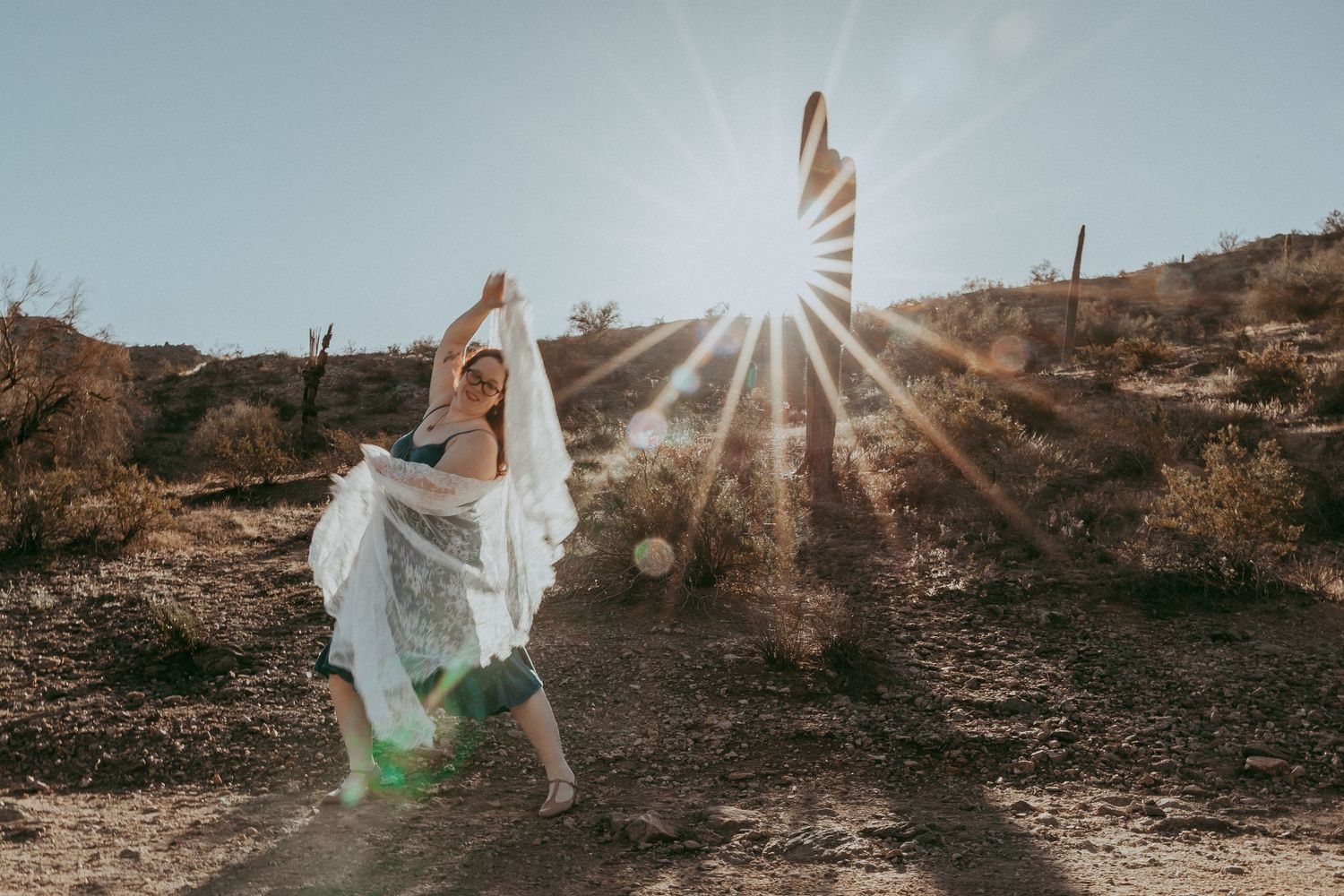 A woman dances with lace blanket in the desert with sun rays all around. Whitney Popp, Phoenix Arizona photographer.