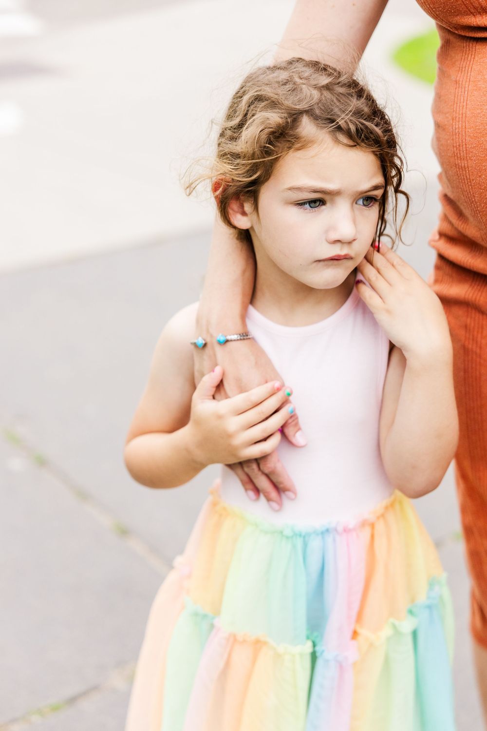 A young child wearing a pink and rainbow colored dress poses in a series of candid wardrobe photos.