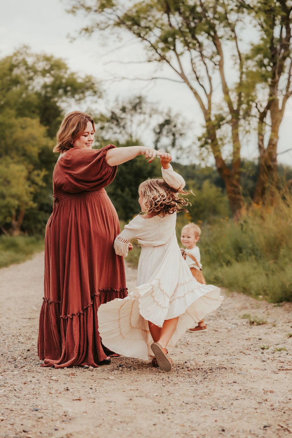 Dancing and twirling moments captured between family members wearing burgundy and white outfits in an outdoor setting.