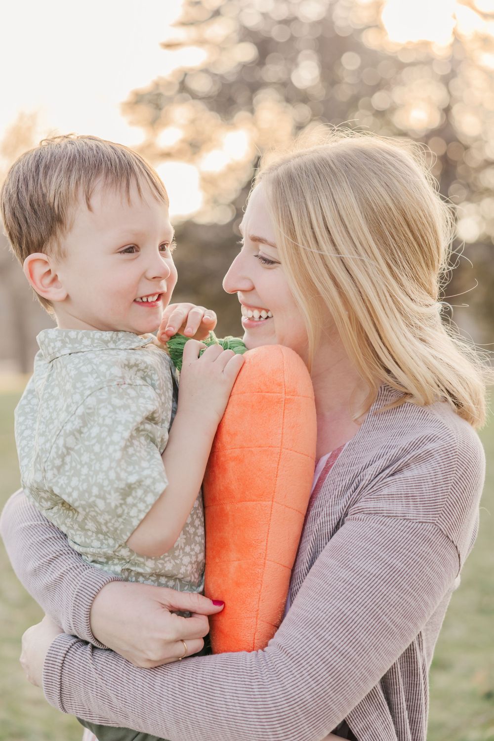 Joyful moment with plush carrot toy in sunny outdoor setting.