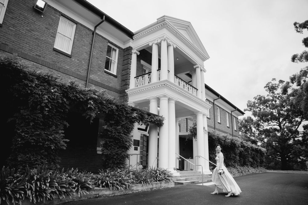 Black and white photo of a bride at a historic building with classic colonial architecture.