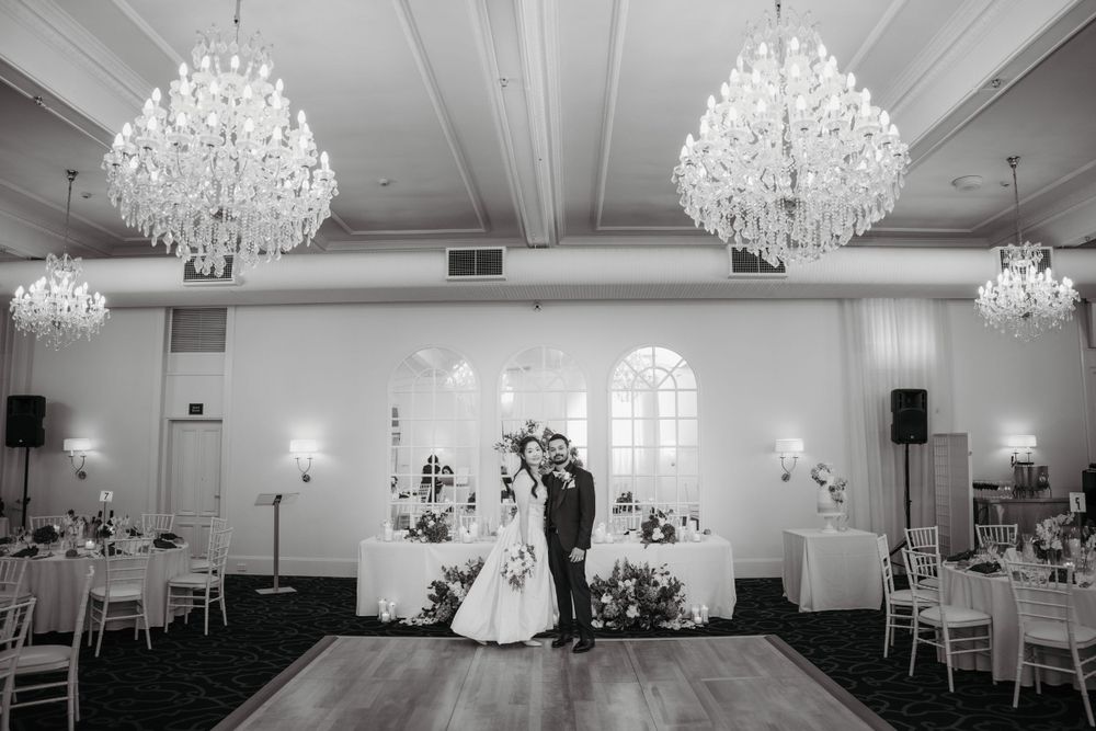 An elegant ballroom wedding reception with crystal chandeliers and classic white decor.