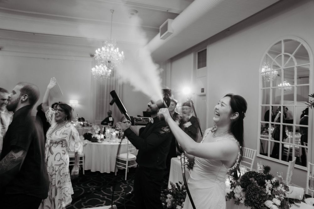 Wedding reception celebration with guests using smoke effects under crystal chandeliers.