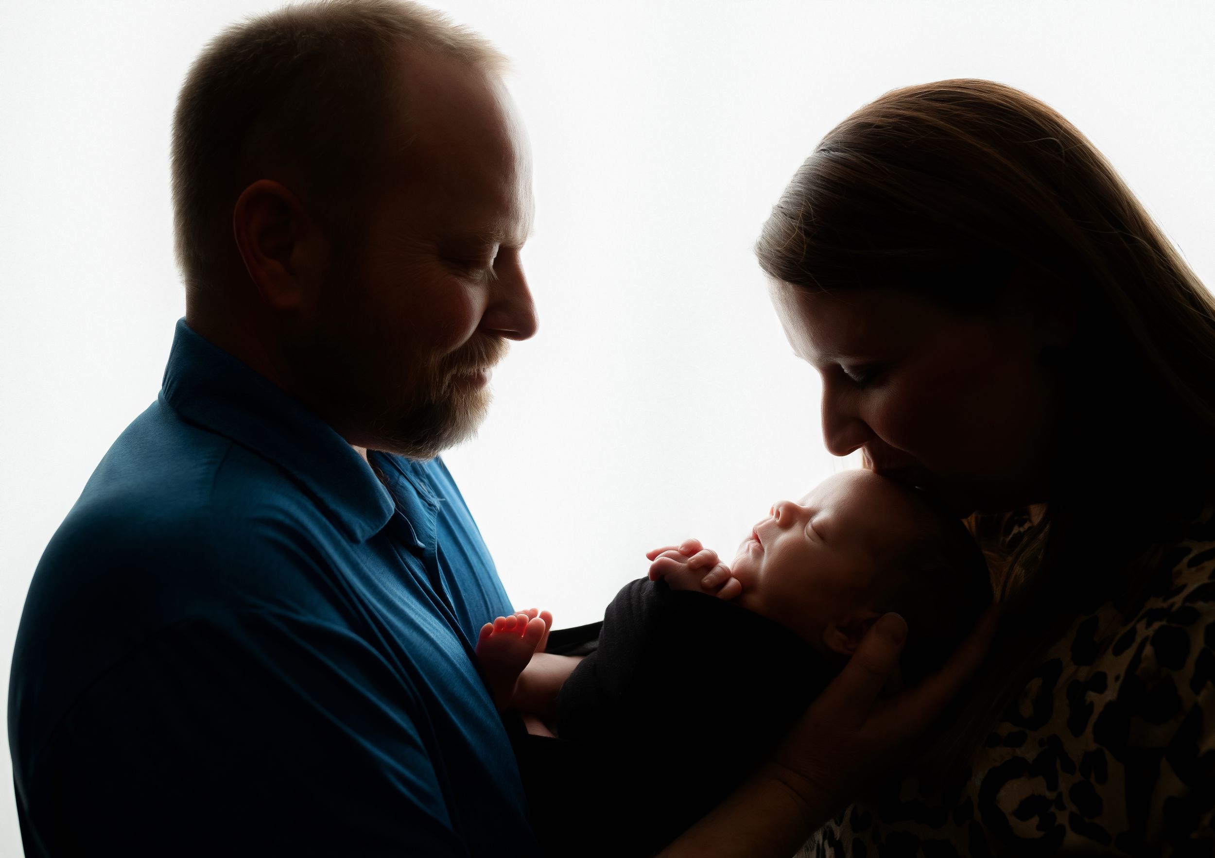 Mom and Dad's backlit shot kissing the baby. Greenville SC newborn photographer, Easley SC newborn photographer