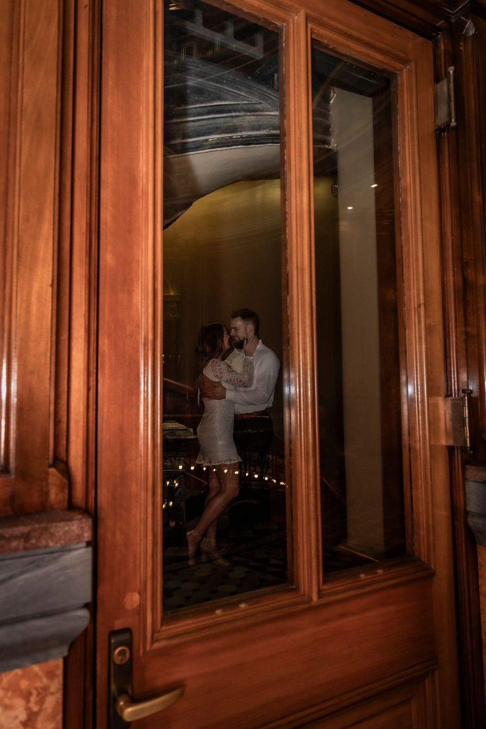 Engaged couple interacting through a staircase doorway at the Iowa State Capital.
