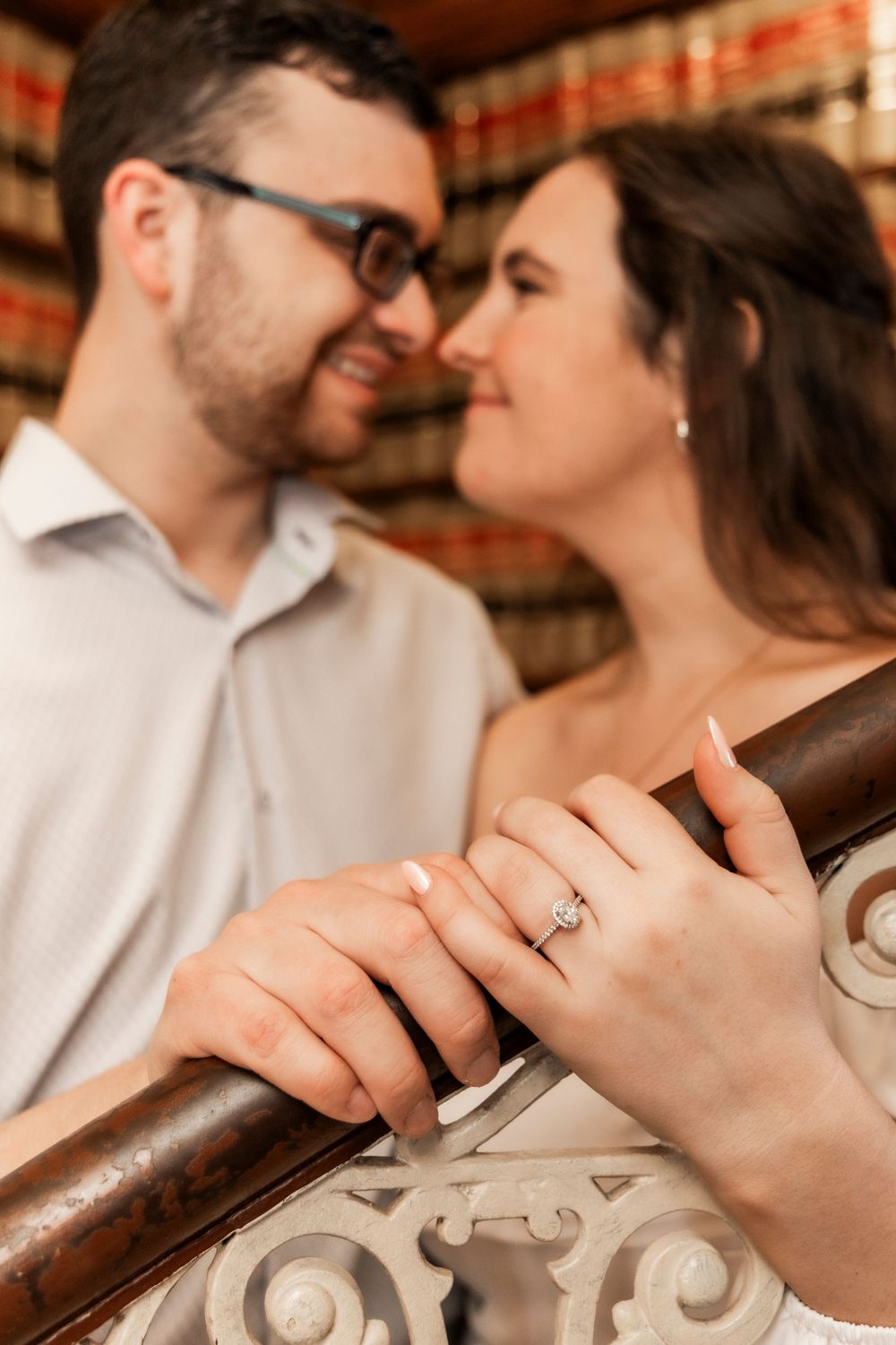 Engaged couple looking at each other with engagement ring in foreground at the Iowa State Capital.