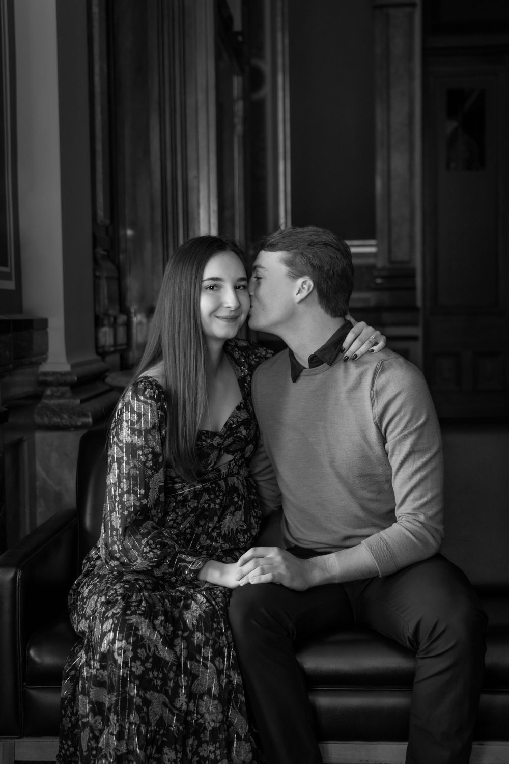 Engaged Couple sitting near a large window at the Iowa State Capital.