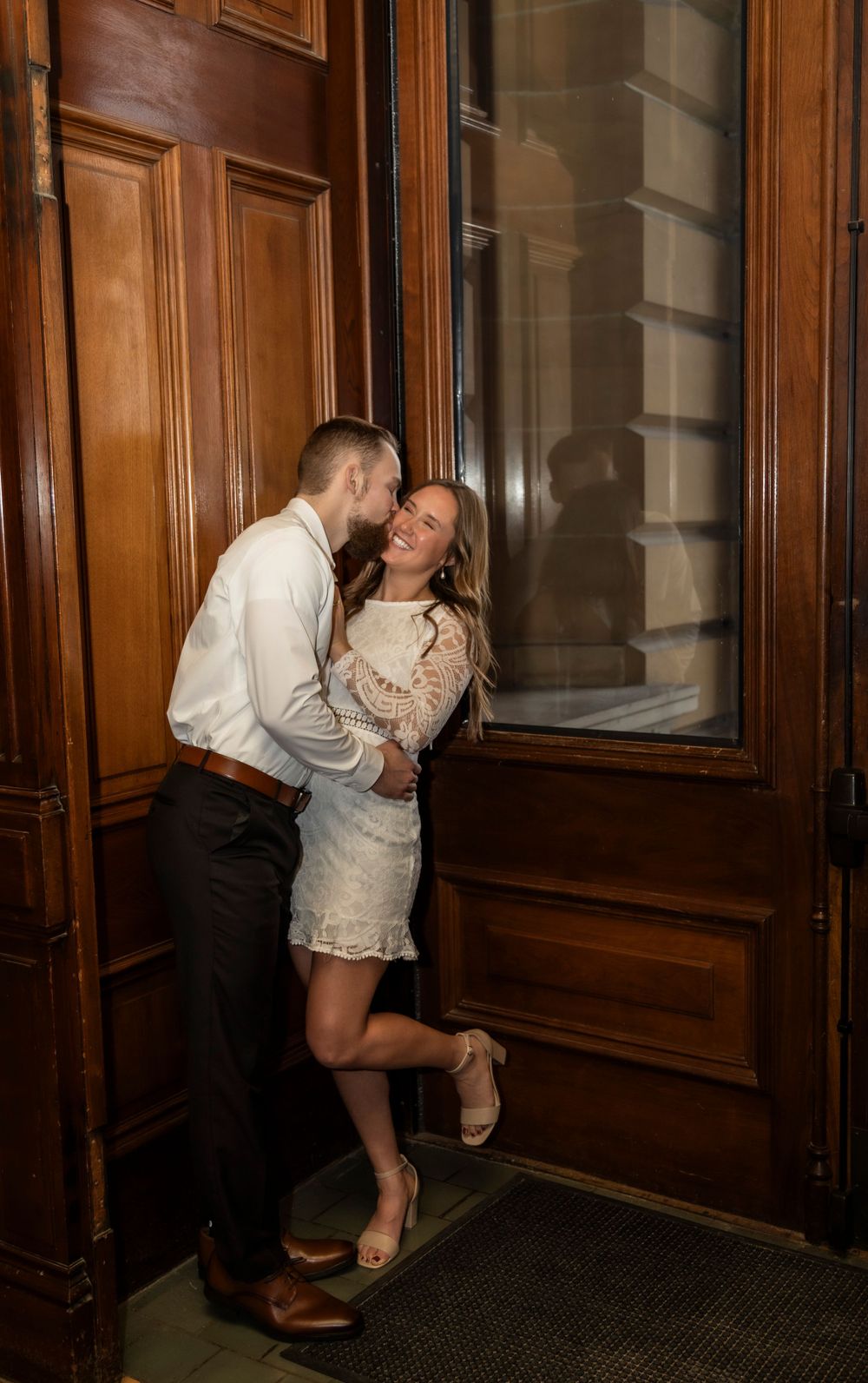 Man kissing engaged fiance on the cheek at the Iowa State Capital Building.