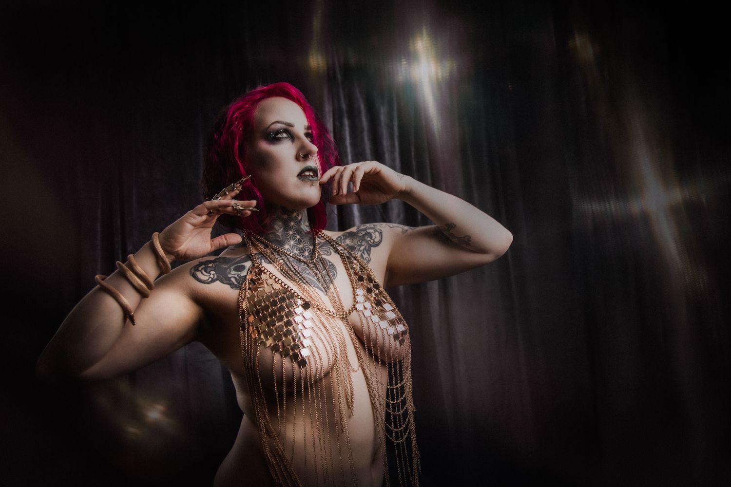 Theatrical portrait featuring red hair and artistic body paint against dark background.