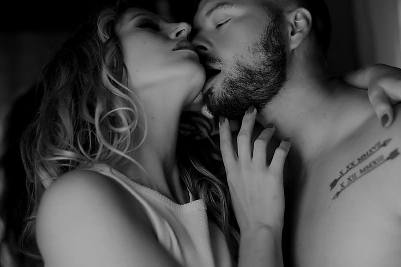 Black and white intimate portrait of an affectionate couple embracing in a sensual moment.