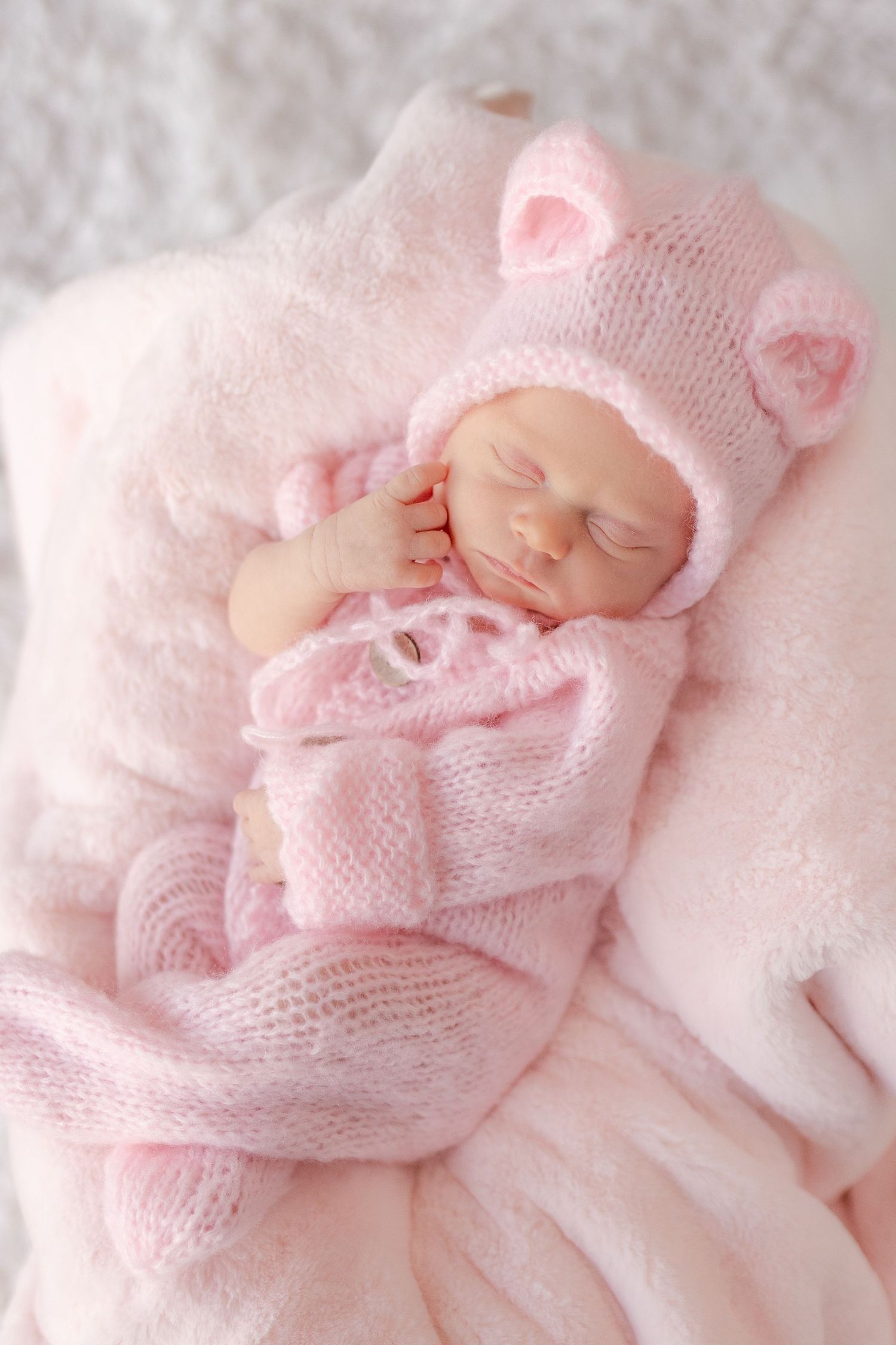 adorable infant girl baby wearing a pink knitted sweater outfit with hat with ears