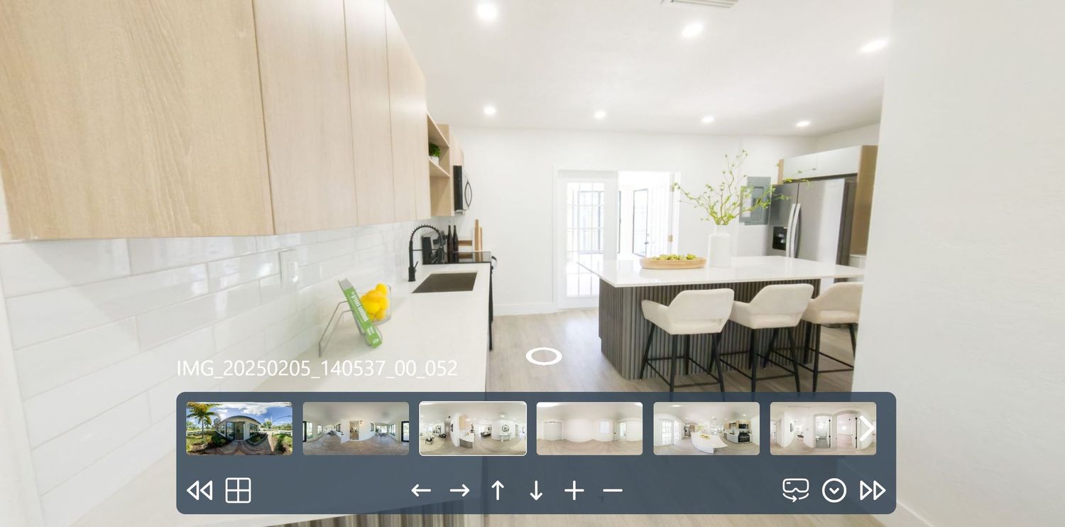 Modern open concept kitchen with white cabinets, quartz countertops and integrated dining bar in a bright interior space.