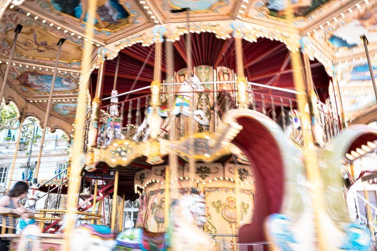 Motion-blurred carousel horses spin on traditional fairground merry-go-round.