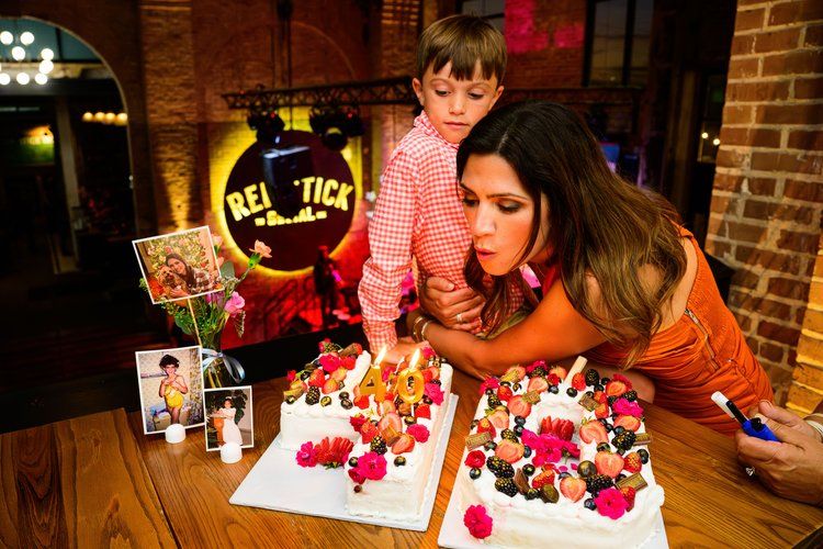Birthday celebration with colorful floral cakes on wooden table in rustic setting.