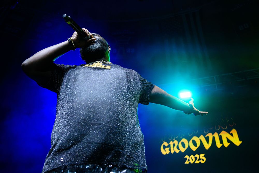 Hip hop concert performer silhouetted against blue stage lighting with 'GROOVIN 2023' text overlay.