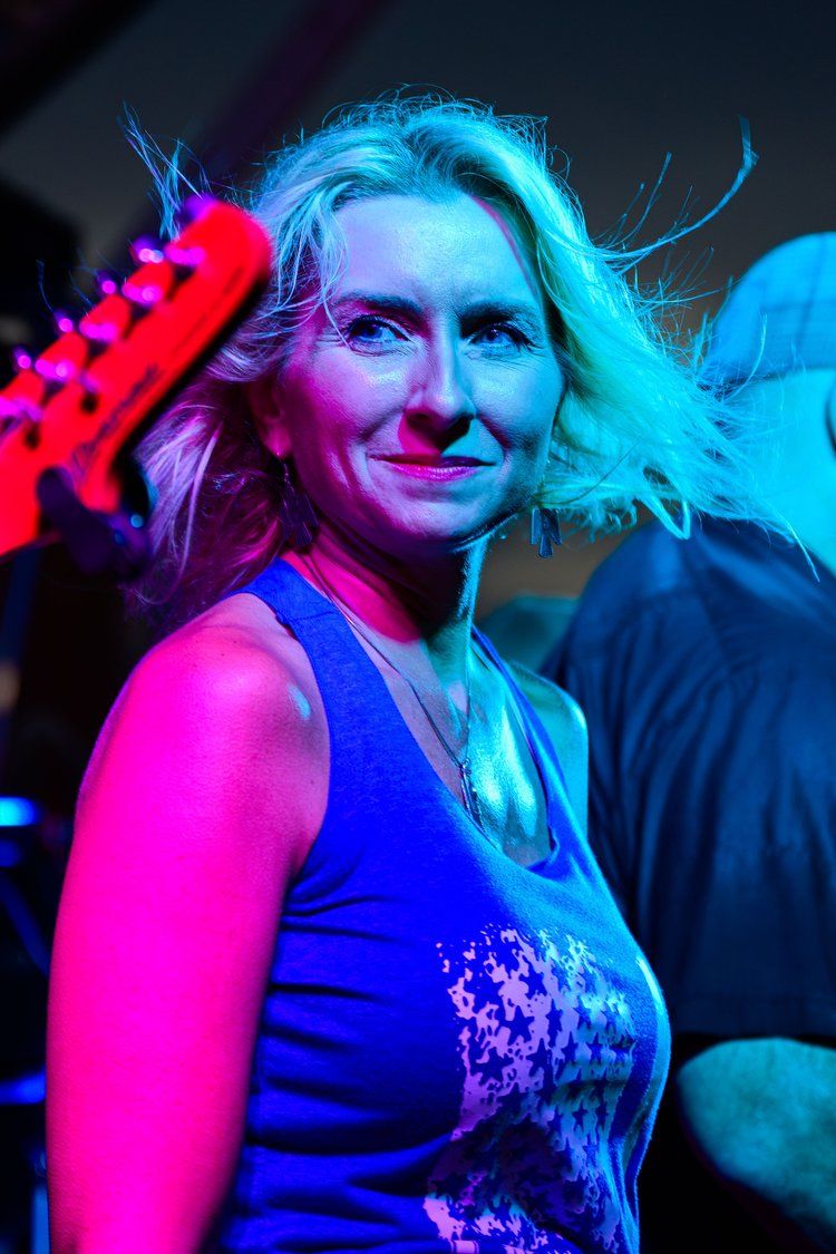 Concert scene with blue and pink neon lighting creates vibrant nightclub atmosphere.