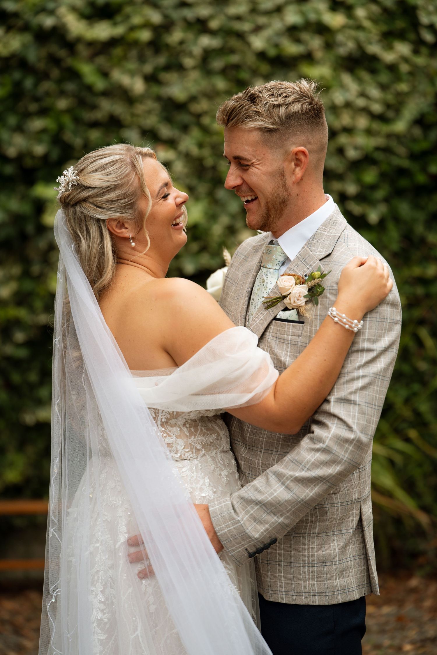 Candid wedding moment against a lush green ivy wall backdrop.