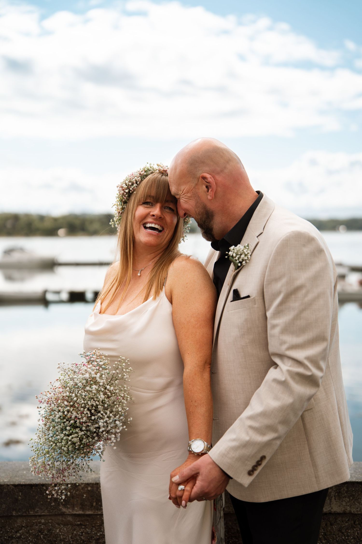 A couple shares a romantic moment by the waterfront on their wedding day.