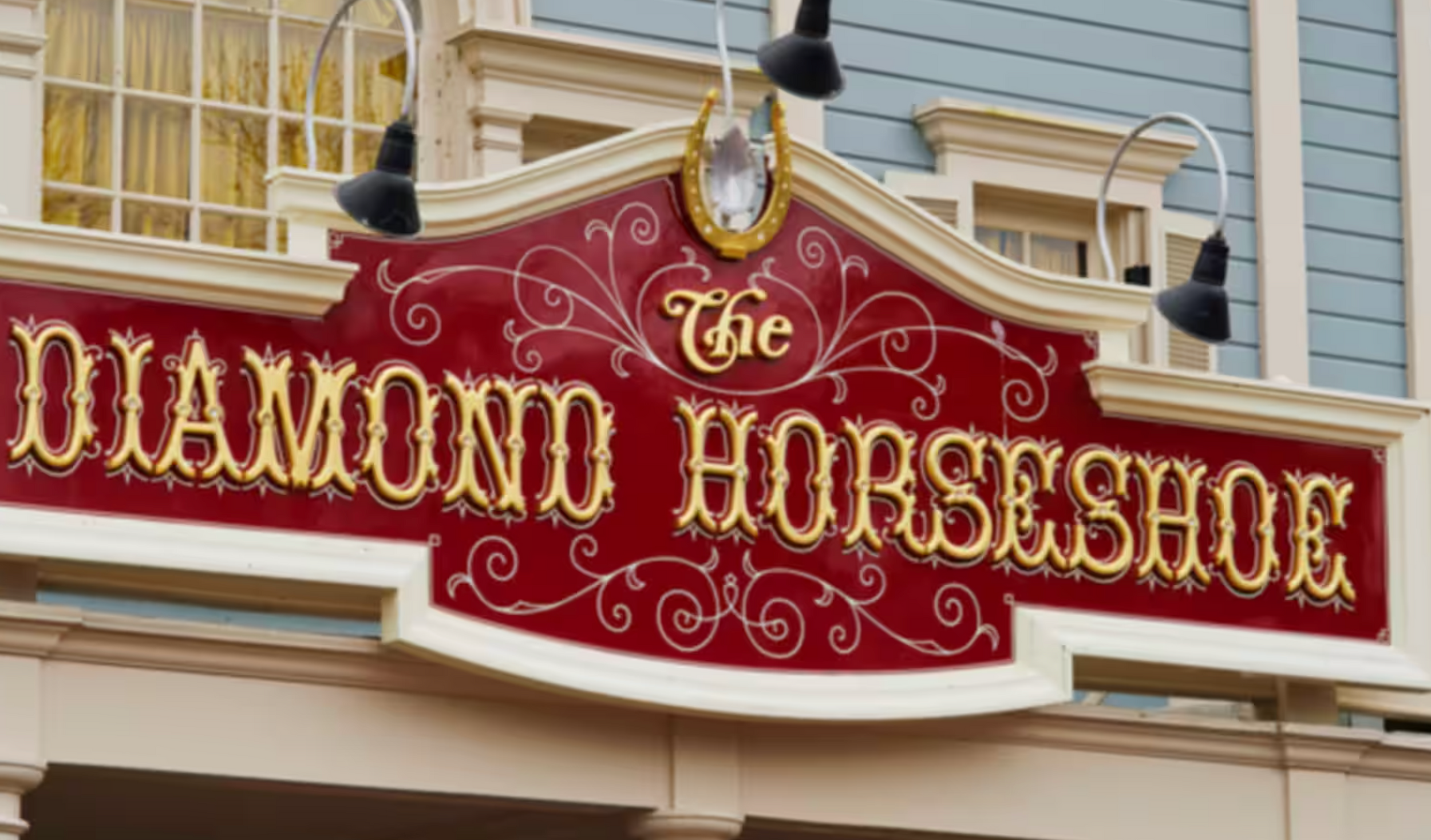 A vintage-style red and gold sign for 'The Diamond Horseshoe' restaurant mounted on a building exterior.