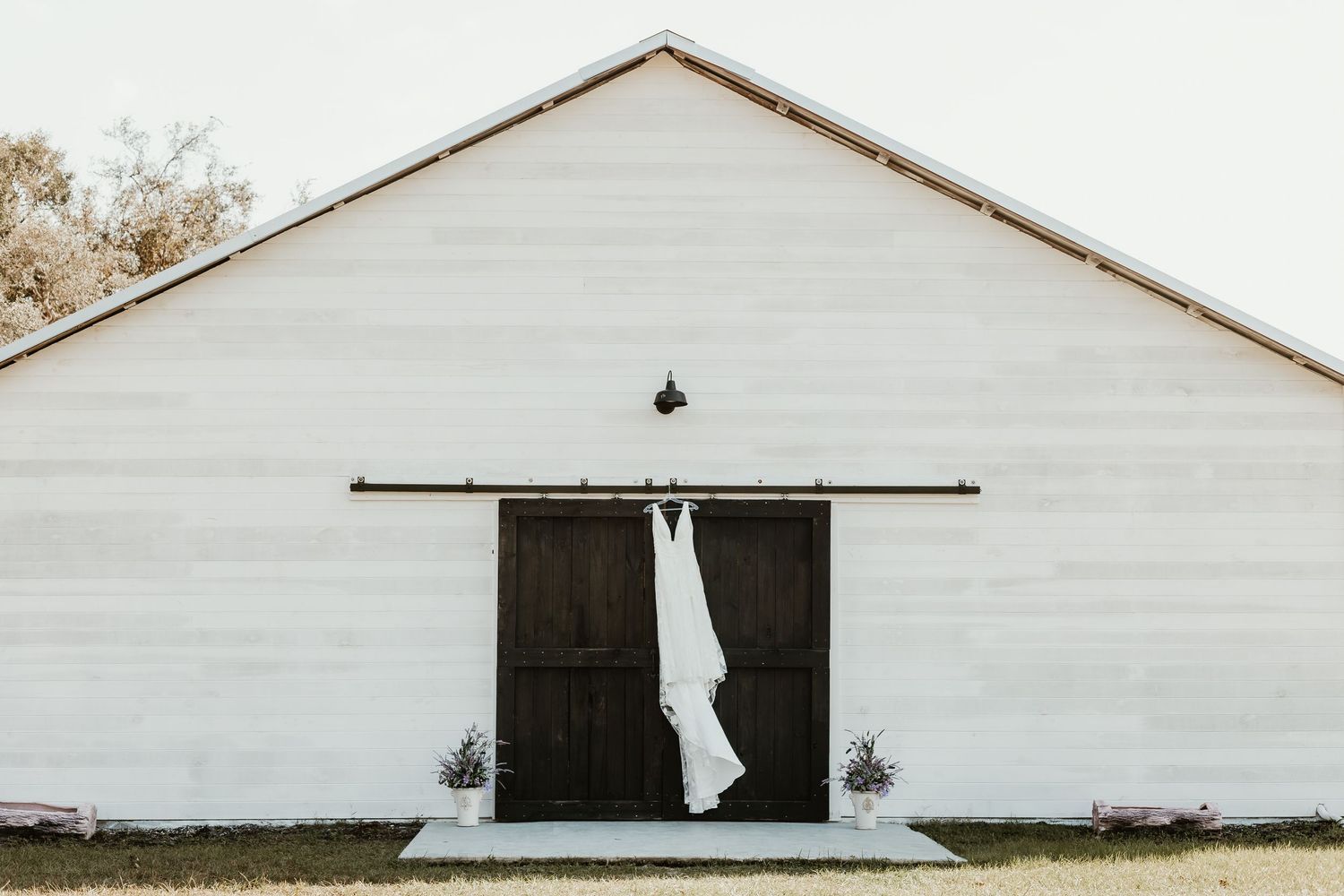 Long white barn-style building with black doors and simple exterior design.