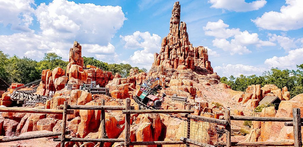 Big Thunder Mountain Railroad rollercoaster track winds through desert-themed rock formations at Disney theme park.