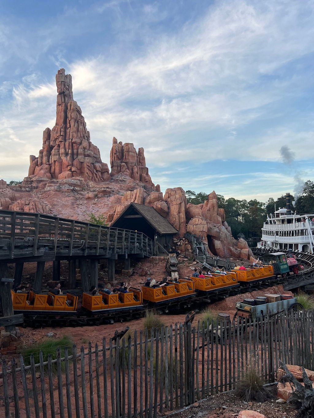 A train ride through Disney's Big Thunder Mountain Railroad attraction with towering red rock formations and cloudy sky.