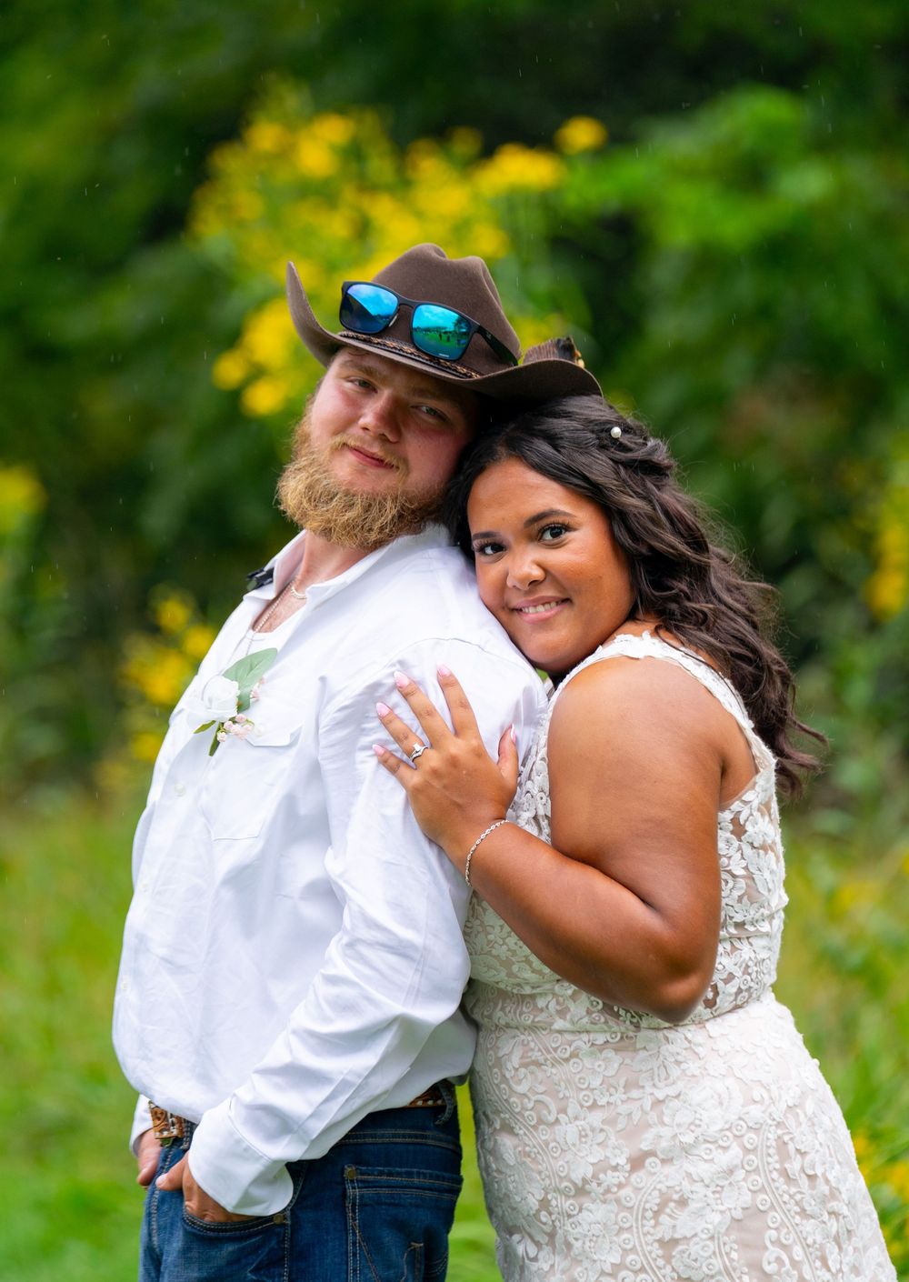 A couple shares romantic moments during their outdoor wedding photoshoot among yellow wildflowers.