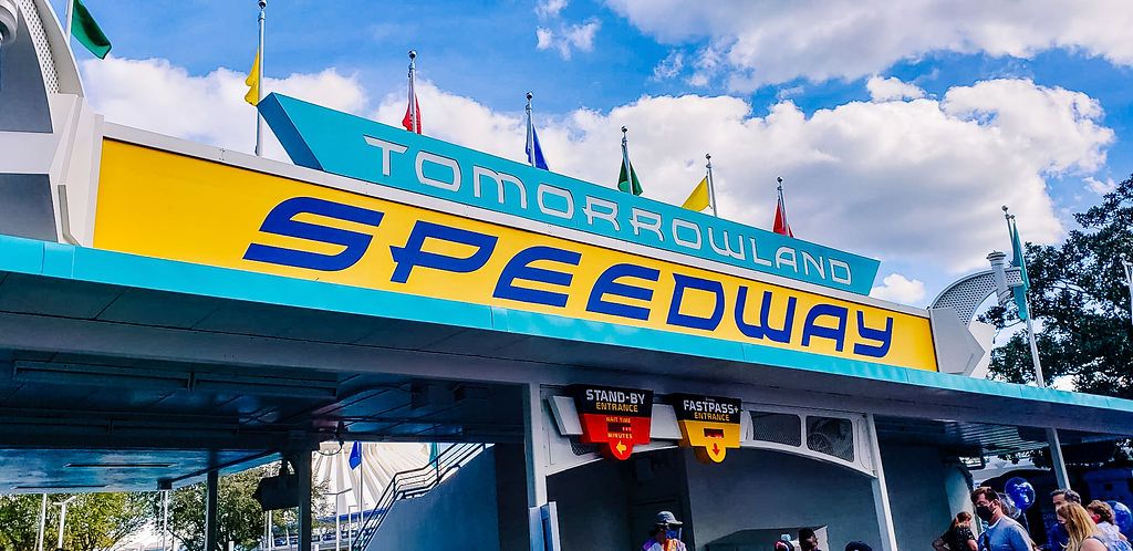 Retro-style Tomorrowland Speedway entrance sign at Walt Disney World against a blue sky with white puffy clouds.