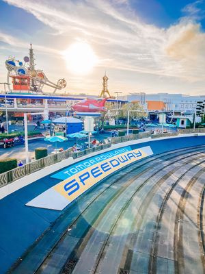 Aerial view of Speedway attraction with blue curved track at Tomorrowland in Disney theme park at sunset.