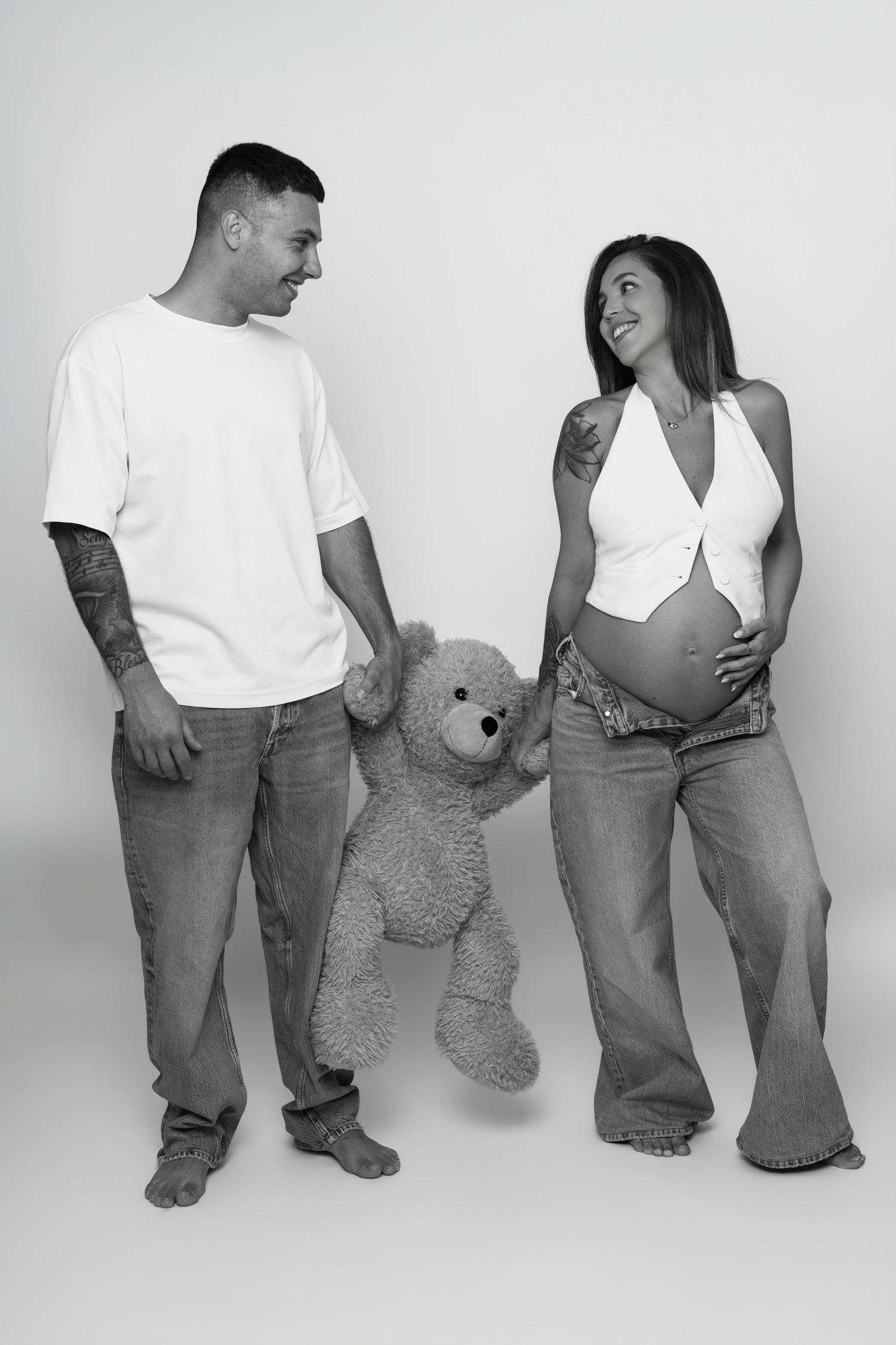 Pregnant woman in black form-fitting dress posing sideways showing her large baby bump.