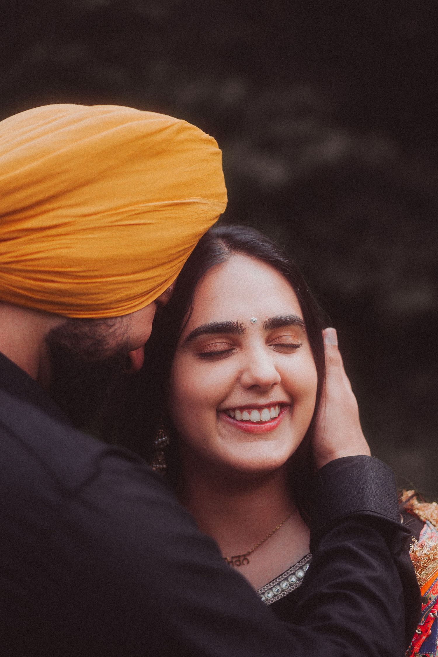 An intimate moment between a couple, with one wearing an orange turban.