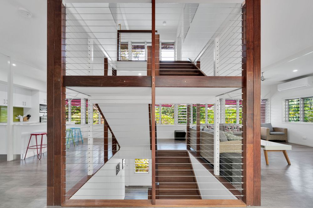 Modern open-concept basement with white walls, exposed wood beams, and polished concrete floors.