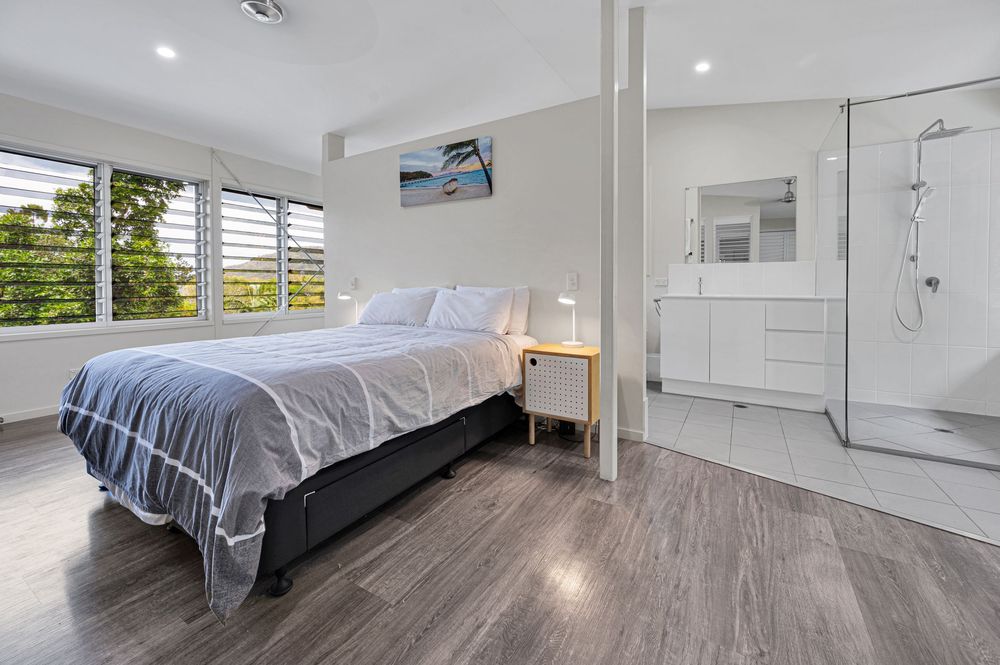 Modern bedroom interior with white walls, dark hardwood floors, and recessed lighting showcases a contemporary design style.