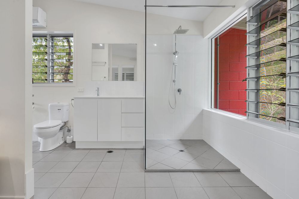 Clean modern laundry room with white cabinets, stacked washer and dryer, and bright red accent wall.