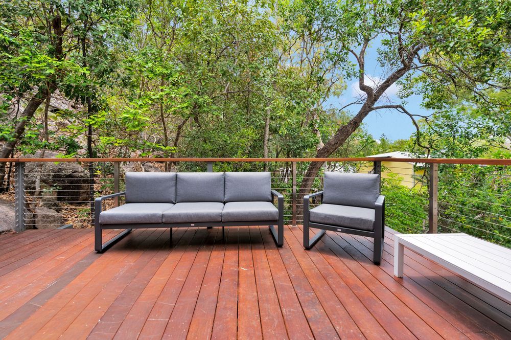 Spacious redwood deck with contemporary lounge seating and black metal railings overlooking a leafy backyard.