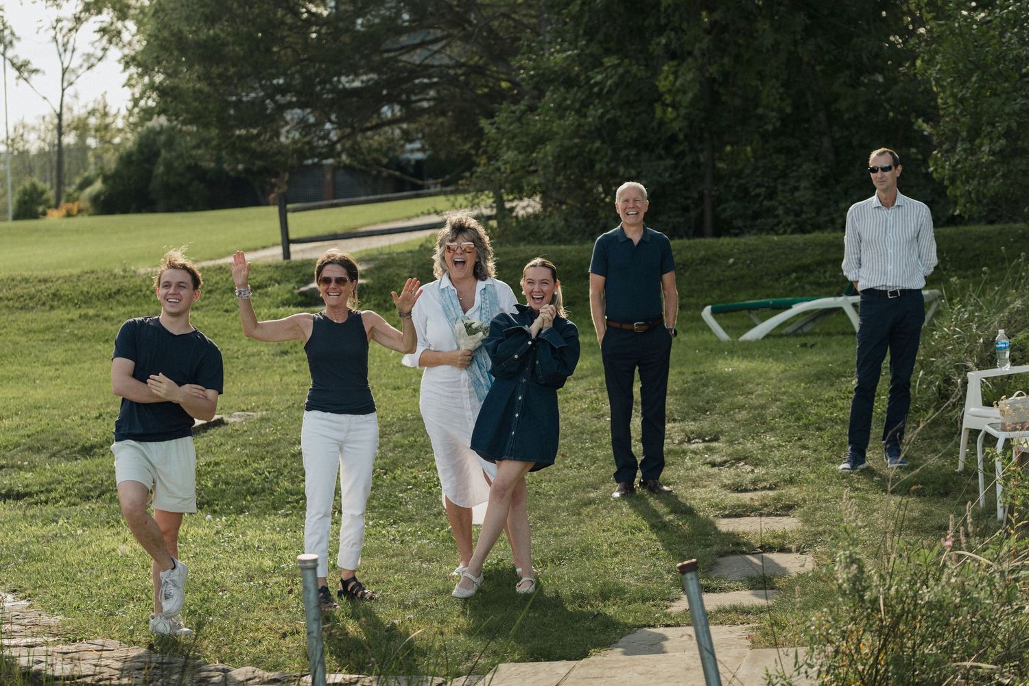 Group of people gathered on a grassy hillside overlooking a lake.