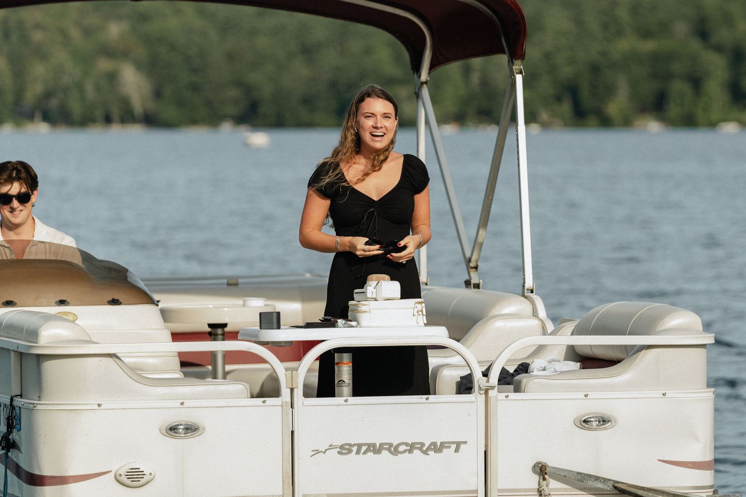 View of multiple pontoon boats on calm waters with passengers enjoying a summer day.