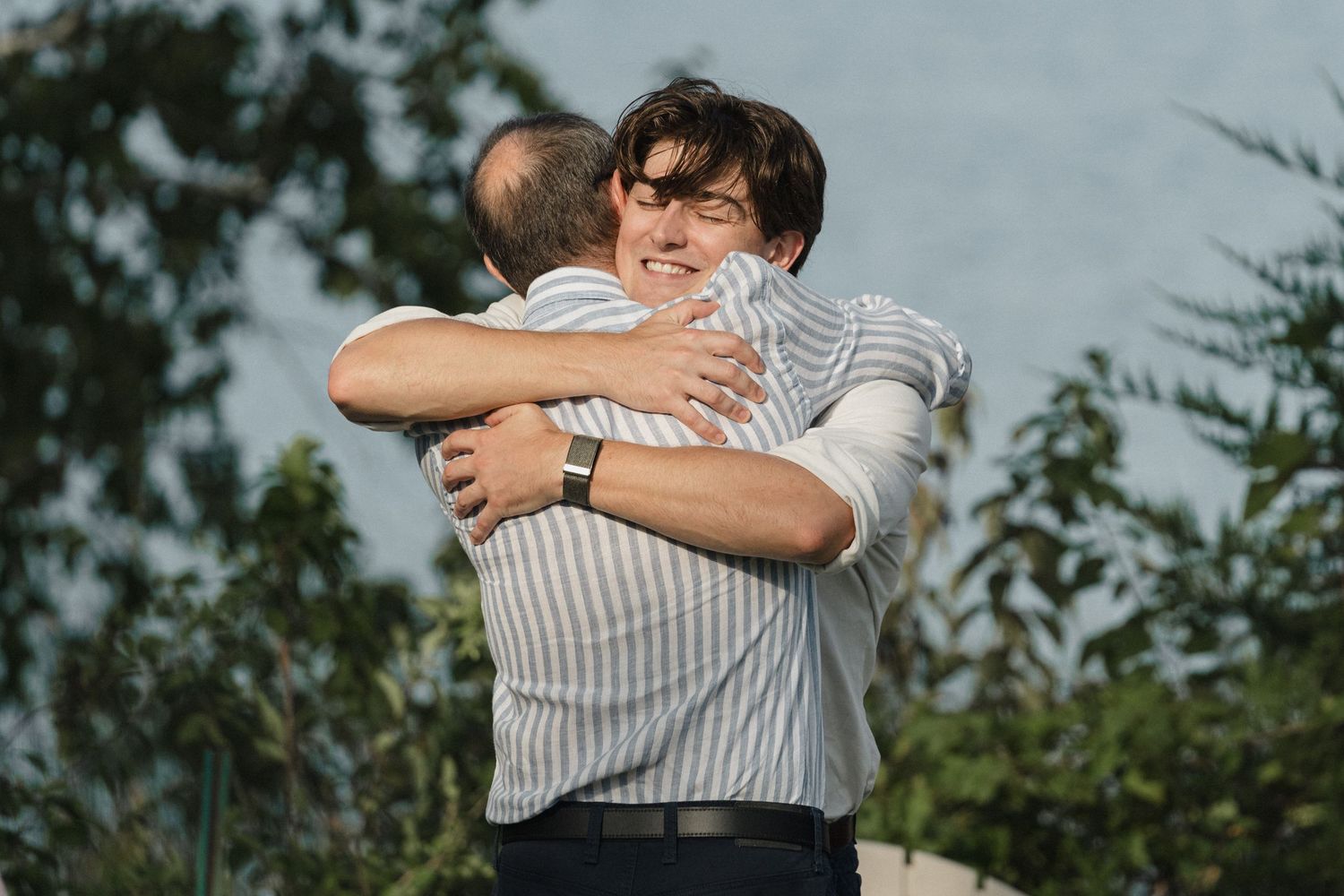 People hugging and sharing tender moments against a natural lake setting.