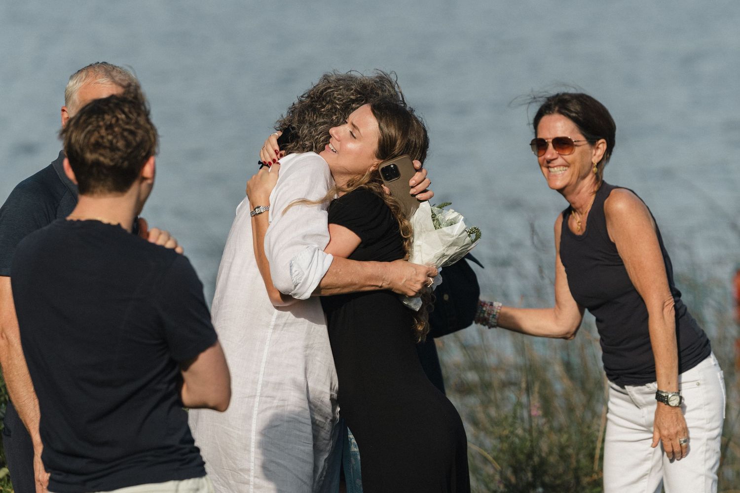 A group dressed in black and white attire poses by a scenic waterfront area.