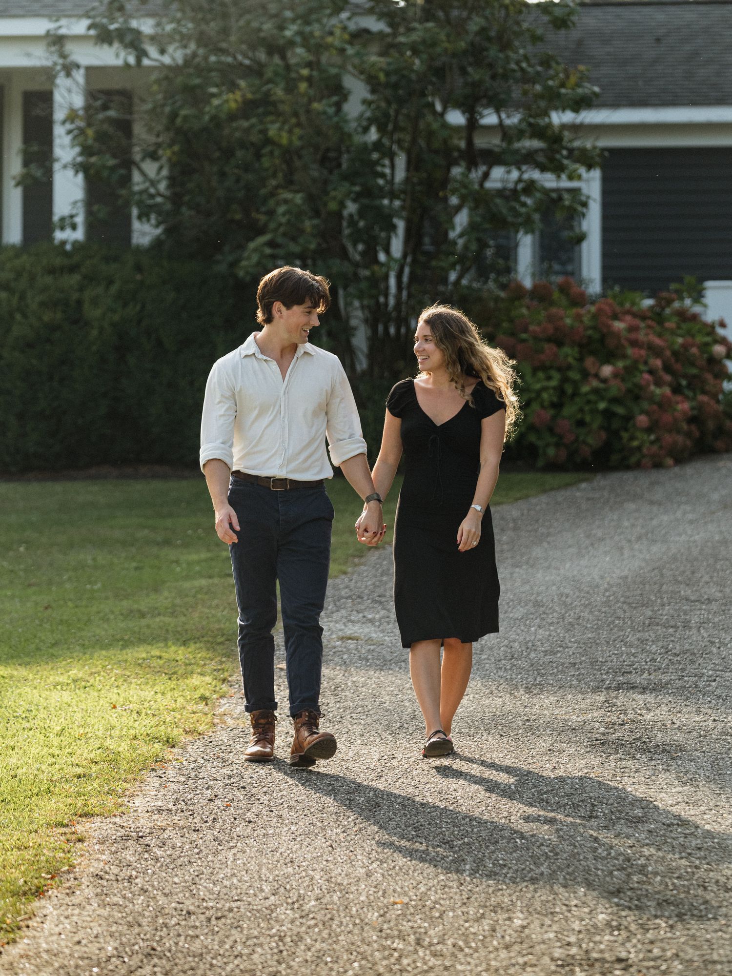 Couples walking together on sunny gravel path near residence.