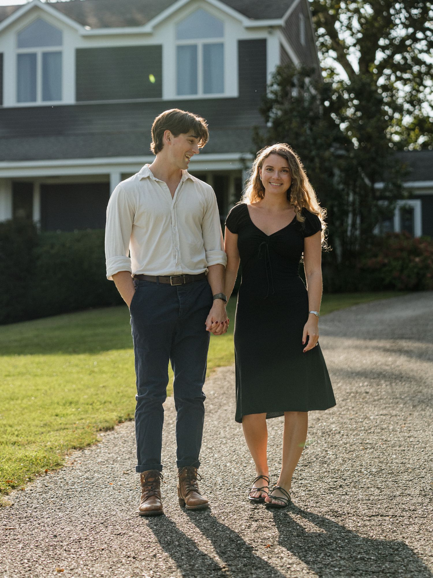 Couple walking together on a gravel path casting long shadows in evening sunlight.