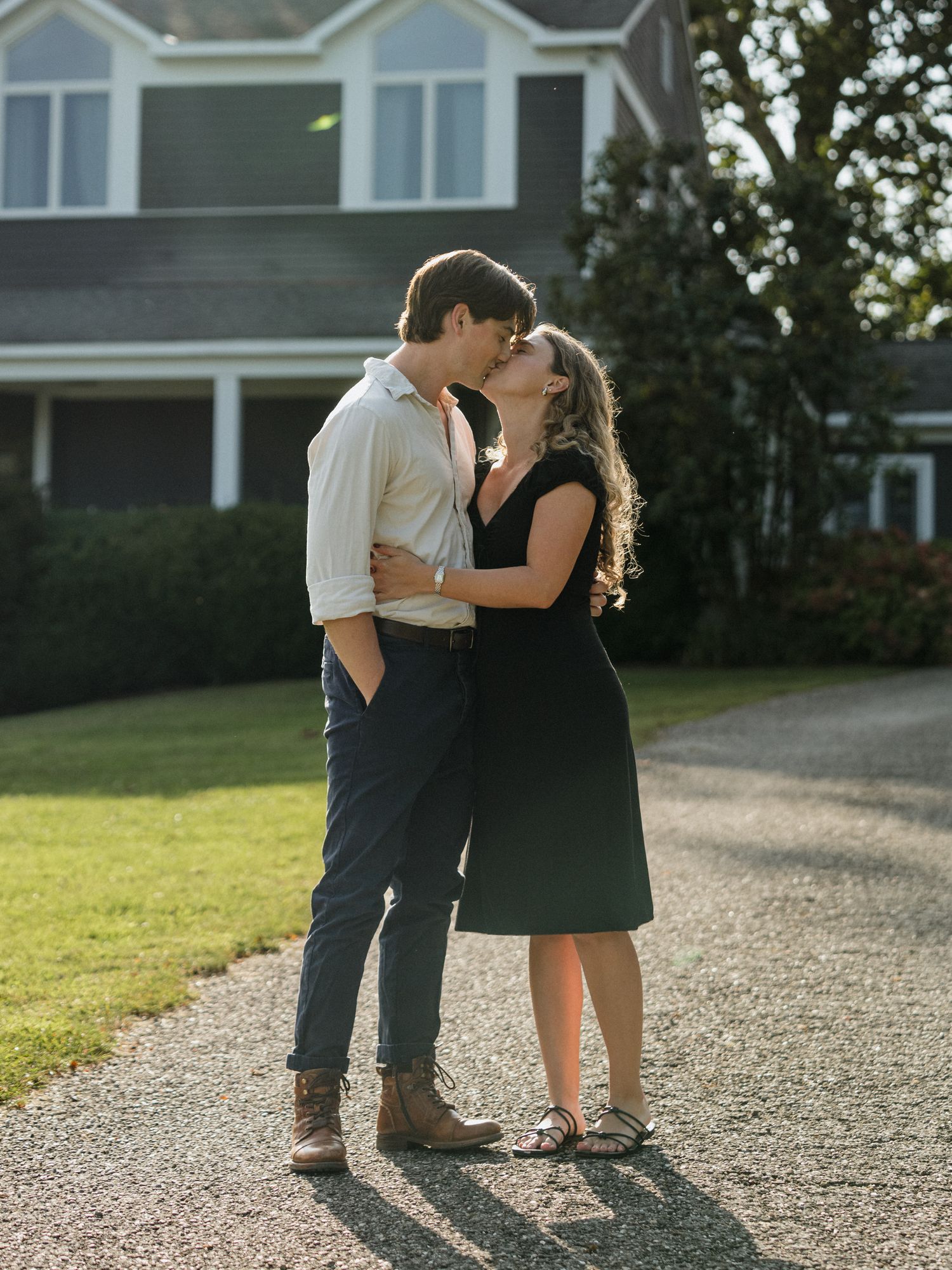 Couple sharing intimate moment on gravel path near house.