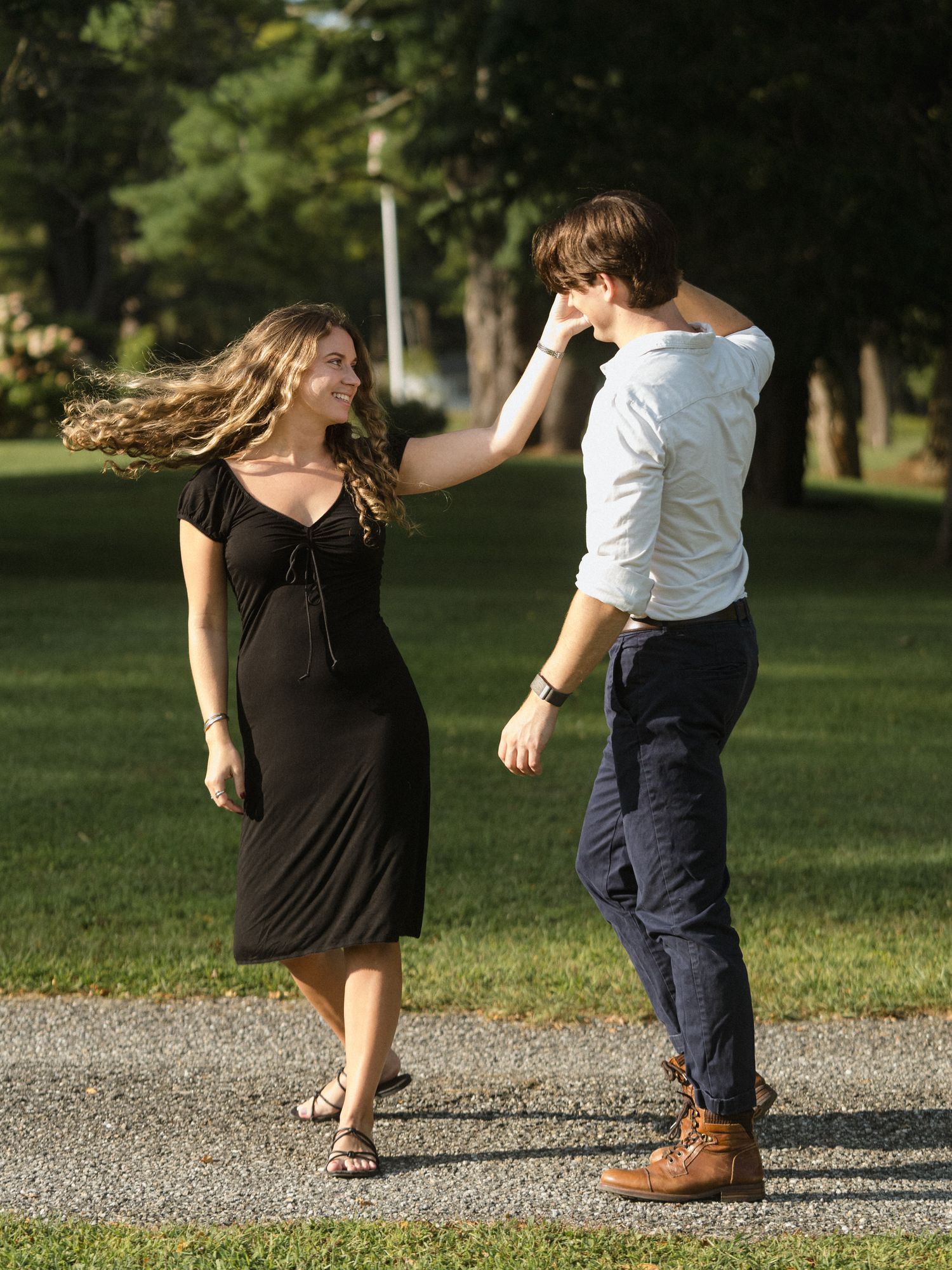 Candid moments of a couple dancing and playing on a path in a park.