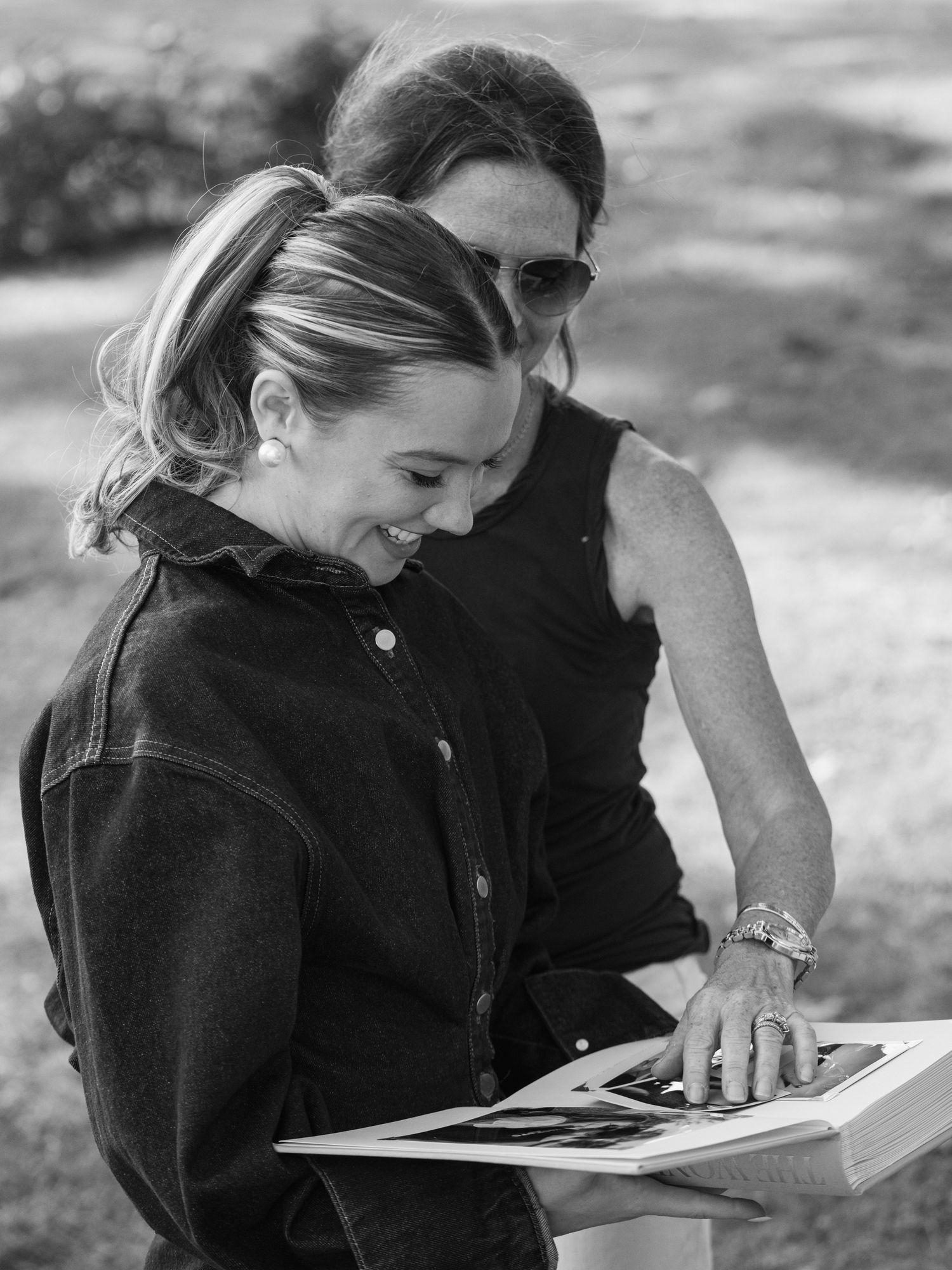 Two individuals sharing a heartfelt moment while looking at a photo album together outdoors.