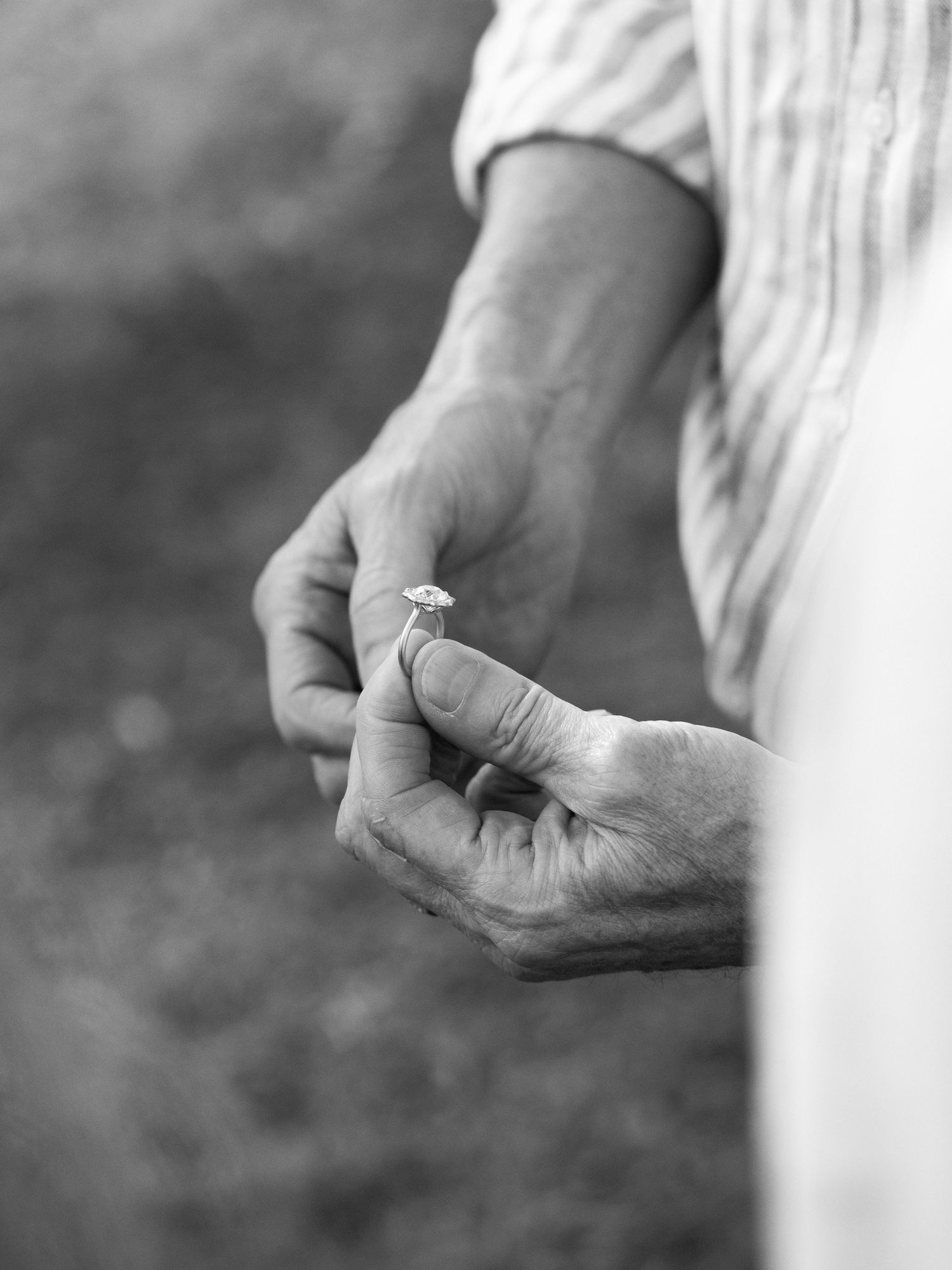 Close-up black and white shot of hands holding an engagement ring.